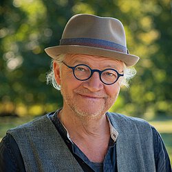 Bild von Dr. med. Michael Druse, Mann mit runder Brille, Hut auf dem Kopf, lächelt